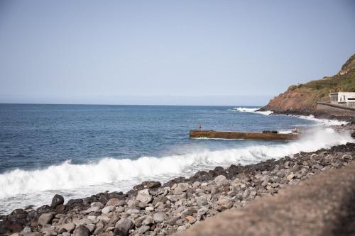 a group of people on a rocky beach near the ocean at Casinha da Vereda by Rent-a-key in Paul do Mar