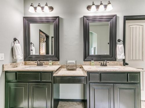 a bathroom with two sinks and two mirrors at Spacious Deer Creek Home with Study and Yard in Edmond
