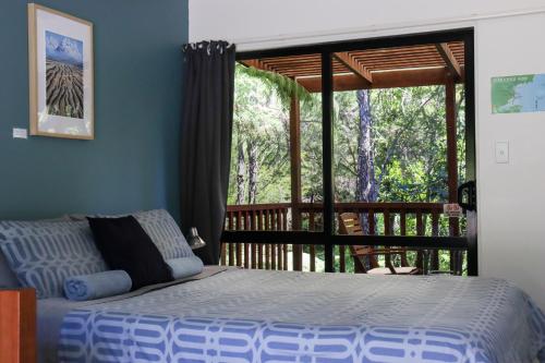 a bedroom with a bed in front of a balcony at Kanuka Ridge Lodge in Marahau