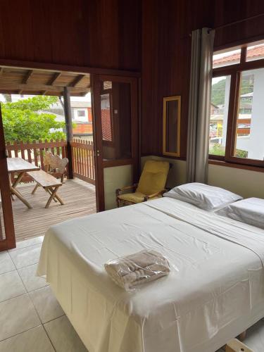 a bedroom with a white bed and a balcony at Guarda Flats in Guarda do Embaú