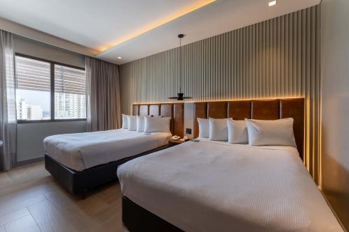 una habitación de hotel con dos camas y una ventana en Hotel Deville Prime Cuiabá, en Cuiabá