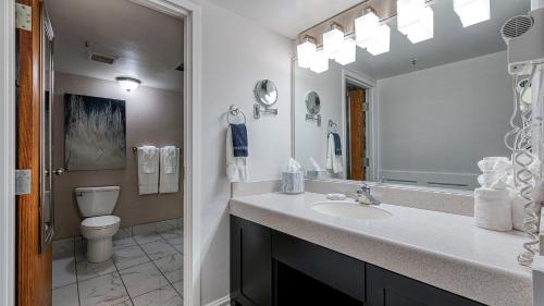a bathroom with a sink and a toilet and a mirror at University Inn in Logan