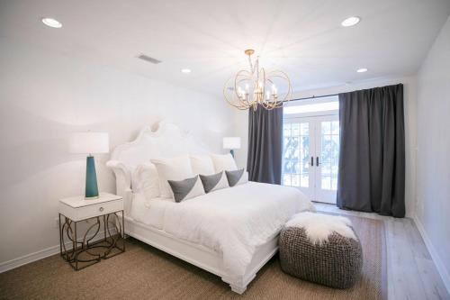 a white bedroom with a white bed and a chandelier at Marée Mason in Ocean Springs