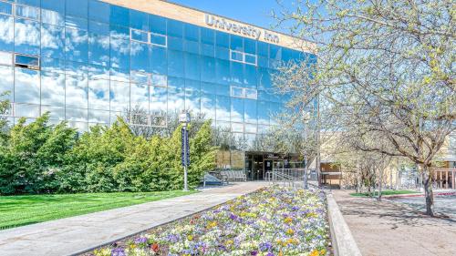 a large glass building with flowers in front of it at University Inn in Logan