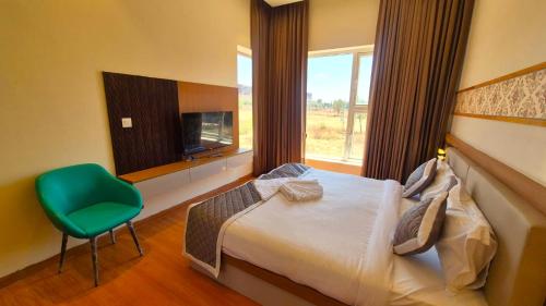 a bedroom with a bed and a green chair at Antilia Inn in Badami
