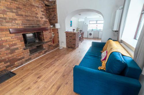 a blue couch in a living room with a brick fireplace at Spacious 4-bedroom - 2 full Bathrooms home - Private off-road Parking - Centrally located in Bridgend