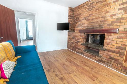 a living room with a blue couch and a brick fireplace at Spacious 4-bedroom - 2 full Bathrooms home - Private off-road Parking - Centrally located in Bridgend