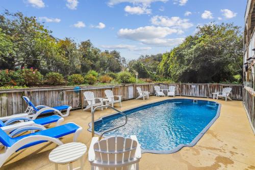 a patio with a swimming pool and chairs and a table at 3675 - Seaducktion in Duck