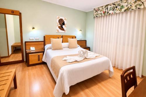 a bedroom with a bed with towels on it at Hotel Spa Galatea in Burela de Cabo