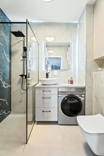 a bathroom with a washing machine and a sink at MDM Apartments in Gdańsk