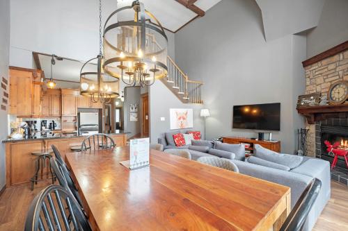 a kitchen and living room with a large wooden table at Les Manoirs 3bdrs W Pool & Hottub Near Village in Mont-Tremblant
