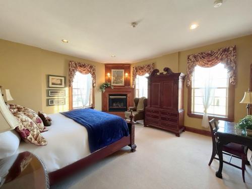 a bedroom with a bed and a desk and windows at The Port Hotel in Port Washington