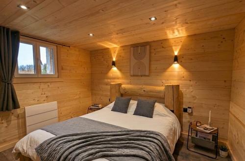 a bedroom with a bed in a wooden cabin at La Clochette d'Hiver Familial et espace Détente in Cornimont