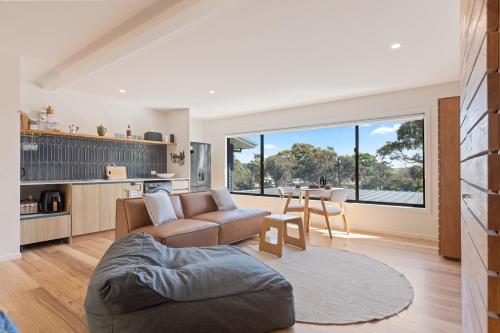 a living room with a couch and a table at Sun Kissed - As close as you get to Pambula Beach in Pambula Beach
