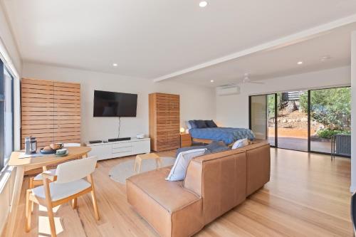 a living room with a couch and a table at Sun Kissed - As close as you get to Pambula Beach in Pambula Beach