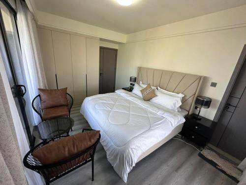 a bedroom with a large white bed and a chair at The Nairobi Experience in Nairobi