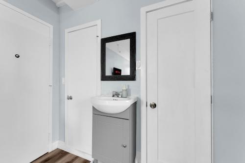 a white bathroom with a sink and a mirror at Guestic Hotel at Queen West in Toronto