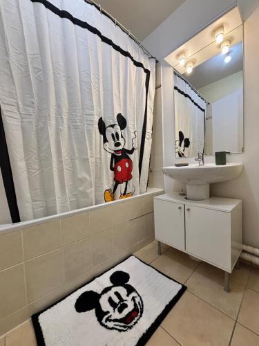 a bathroom with a mickey mouse shower curtain and a sink at Disneyland Family Studio in Magny-le-Hongre