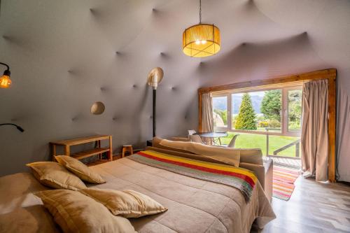 a bedroom with a large bed with a large window at Glamping Vulcanche in Villa Traful