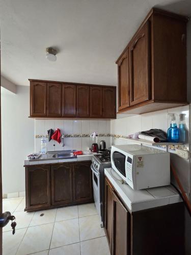 a kitchen with wooden cabinets and a stove and a microwave at Candela Apartment PUNO in Puno