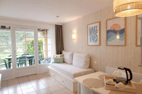 a living room with a couch and a table at Appartements au coeur du golf, proche du lac et vélodyssée in Biscarrosse