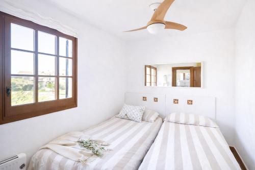 a bed in a white room with a window at EcoHome Menorca in Cala en Porter