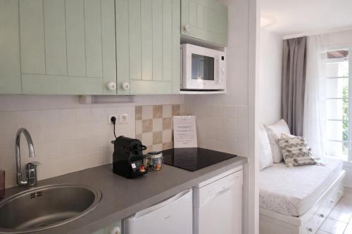 a kitchen counter with a sink and a microwave at Appartements au coeur du golf, proche du lac et vélodyssée in Biscarrosse