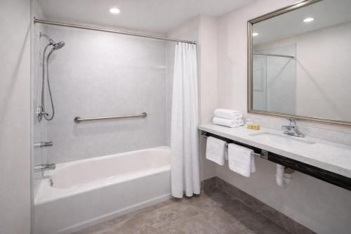 a bathroom with a tub and a sink and a mirror at Super 8 by Wyndham Bakersfield CA Near Airport in Bakersfield