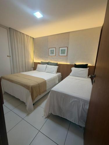 a hotel room with two beds in a room at Apartamento em Resort para família in Barra de São Miguel