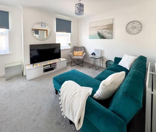 a living room with a green couch and a flat screen tv at The Sashes - Cozy Apartment - FREE Parking - Ultrafast WIFI - Smart TV - Netflix - sleeps up to 6! Close to Poole Town Center & Sandbanks & Bournemouth in Poole