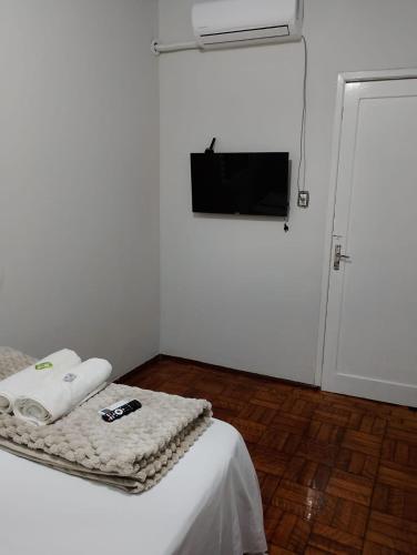 a white room with a bed and a flat screen tv at Hotel Linassi in Cruz Alta