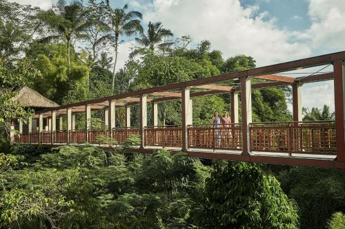 zwei Menschen gehen über eine Brücke über einen Wald in der Unterkunft Four Seasons Resort Bali at Sayan in Ubud