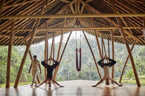 a group of people standing in a thatched room with people at Four Seasons Resort Bali at Sayan in Ubud