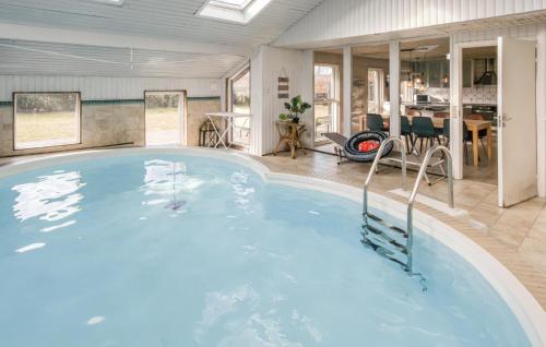 a large swimming pool in a room with a table and chairs at 4 Bedroom Amazing Home In Ørsted in Ørsted