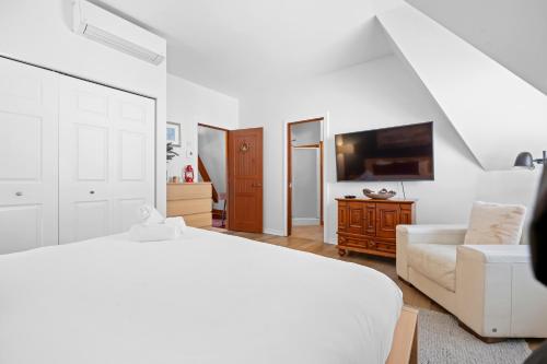 a white bedroom with a bed and a couch at Le Plateau Ski Inout W 3bdrs W Pool Access in Mont-Tremblant