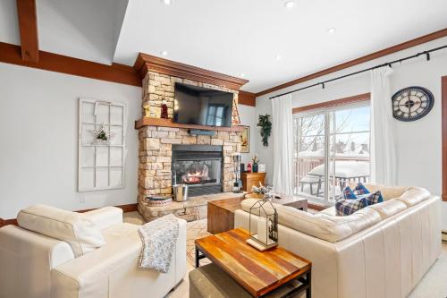a living room with white furniture and a fireplace at Le Plateau Ski Inout W 3bdrs W Pool Access in Mont-Tremblant