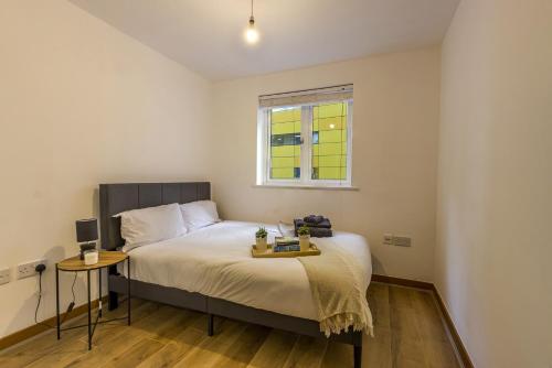 a bedroom with a bed with a table and a window at Luxury 2 Bed 2 Bath Canary Wharf Apartment with Balcony in London