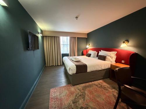 a bedroom with a large bed with a red headboard at HNFC Stays - Harmony Accommodation in Elswick