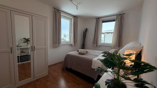 a bedroom with a bed and two windows at Garden Rooms near Munich in Althegnenberg
