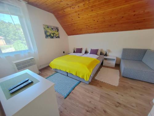 a bedroom with a yellow bed and a couch at Maja Anna Vendégház in Bogács