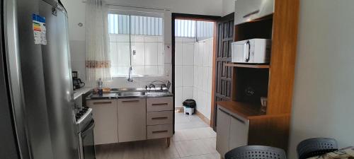 a small kitchen with a sink and a microwave at Suíte aconchego in Guaratuba
