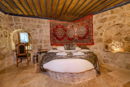 a bedroom with a bed with a rug on the wall at Lubberona Cave Cappadocia in Nar