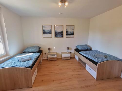 two beds in a room with two tables at Wohnung Werratal Blick in Dankmarshausen
