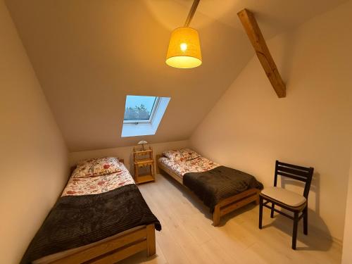 a attic room with two beds and a chair at Apartament u Buki Zator, Skawina, Kraków in Pozowice