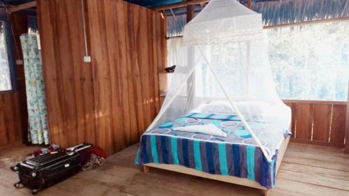 a bedroom with a bed with a canopy and a suitcase at Red Uakari Jungle Lodge in Iquitos