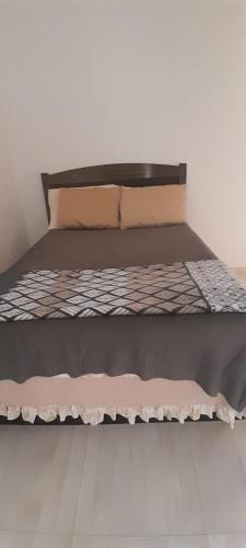 a bed with a wooden headboard and brown sheets at Suíte aconchego in Guaratuba