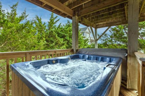 a hot tub on a deck with trees at 8194 - Southern Grace in Waves