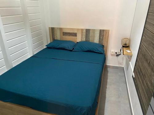 a bed with blue pillows in a small room at Gîte T2 cosy indépendant tout confort in Vieux-Fort