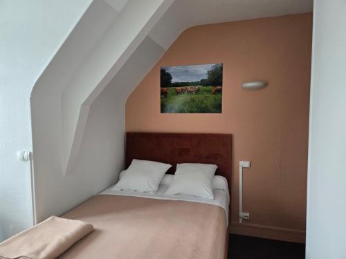 a bed in a room with a painting on the wall at Hotel le Saint Germain in Flers