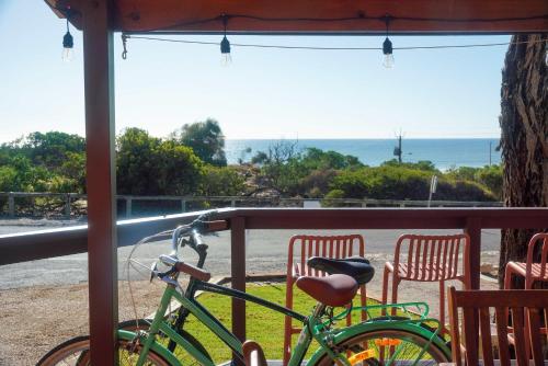a green bike parked on a porch with chairs at Oceanview Beach Shack with Pool & Walk to Dining in Aldinga Beach